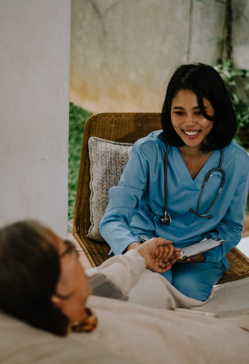 Professional and Compassionate In-Home Nursing Care in New Albany, Ohio A smiling nurse in blue scrubs holds the hand of a senior woman during a compassionate home care visit, symbolizing trust, support, and quality care in New Albany, Ohio.