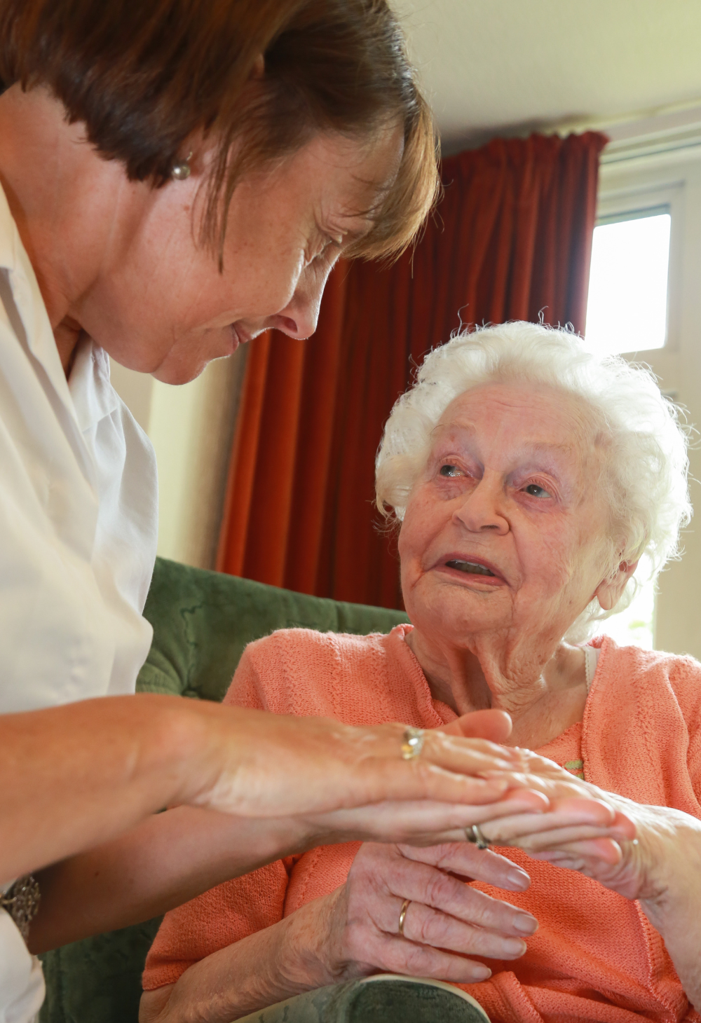 Caregiver gently holding hands with senior woman at home, providing compassionate in-home care and emotional support in Kettering, Ohio.